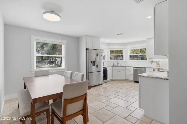 a kitchen with a refrigerator a stove a sink dishwasher with a dining table and chairs