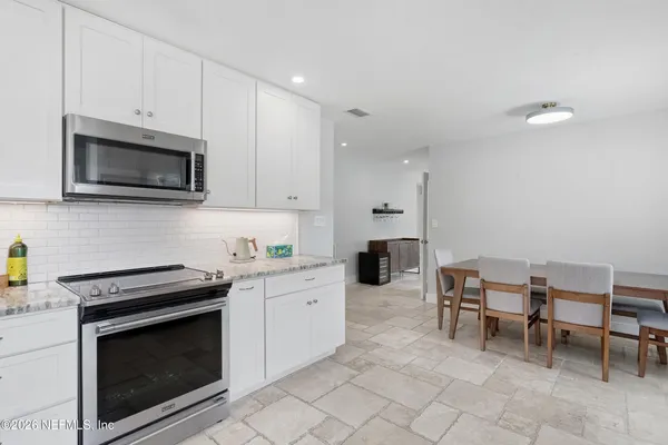 a kitchen with granite countertop a stove top oven microwave and cabinets