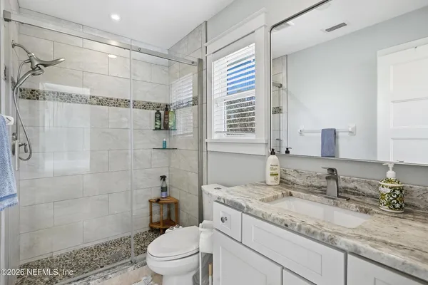 a bathroom with a granite countertop sink a toilet and shower