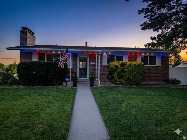 8252 Wood Street Midvale, UT 84047 - Photo 2 of 40 Brick exterior residence featuring a front walkway, manicured lawn, established shrubbery, and a white fence