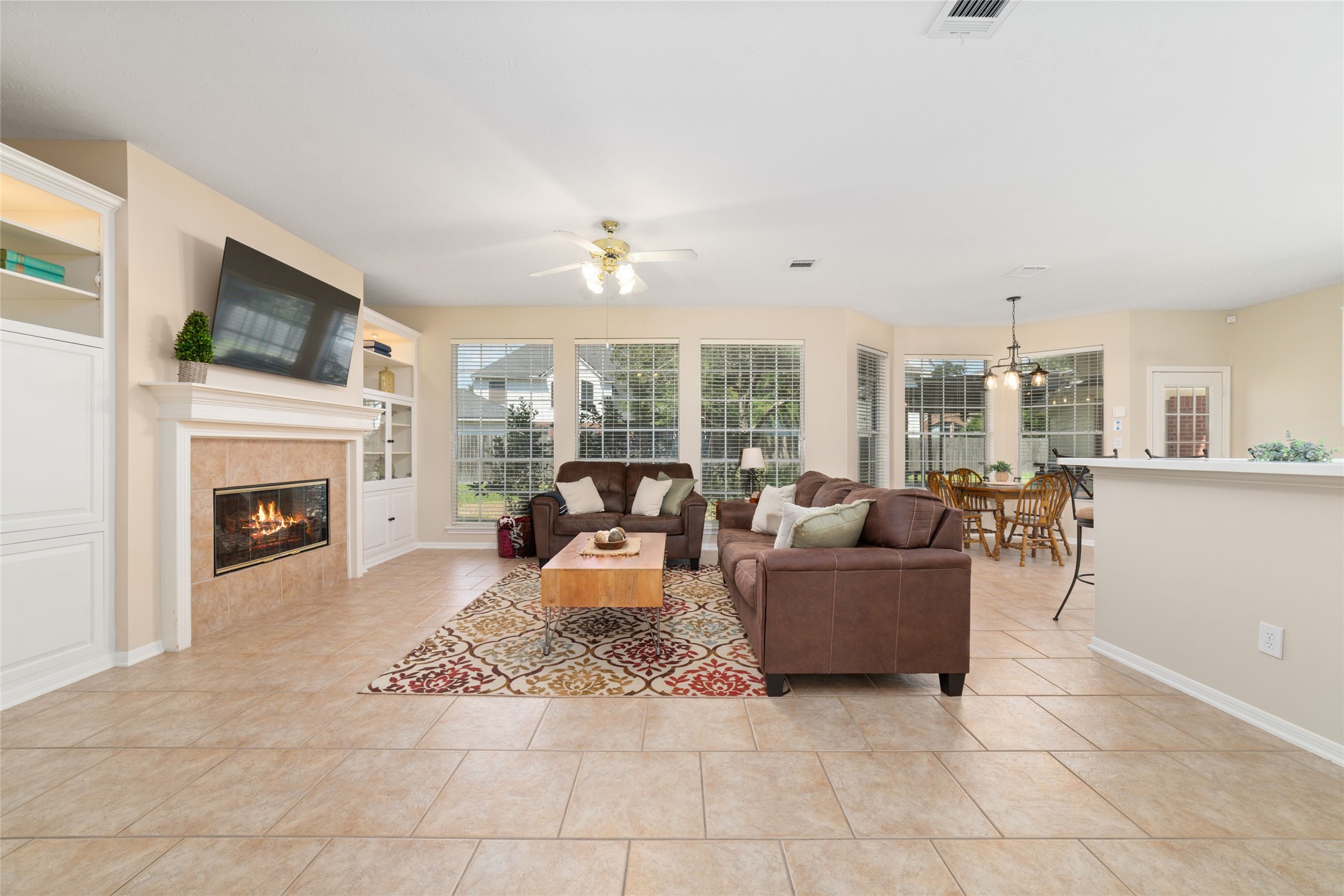 20423 Forest Drive Spring, TX 77388 - Photo 15 of 44 Family room featuring a ceiling fan, a gas log fireplace, and large picture windows providing a scenic view of the backyard.