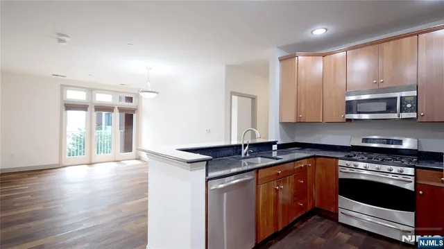 a kitchen with stainless steel appliances granite countertop a stove a sink and a microwave