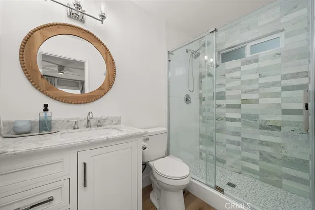 a bathroom with a granite countertop toilet a sink and a mirror