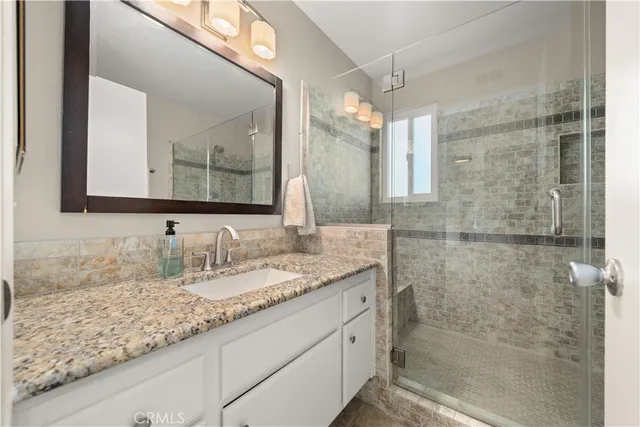 a bathroom with a granite countertop sink a mirror and a shower
