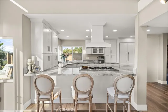a kitchen with kitchen island granite countertop a dining table chairs sink and cabinets