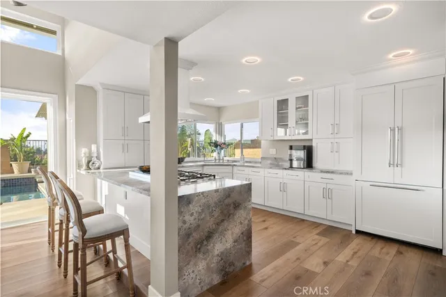 a kitchen with white cabinets and wooden floor