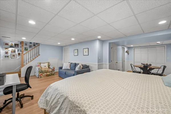 a large bedroom with bed and a chair