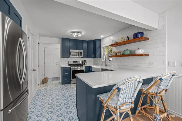 a kitchen with stainless steel appliances granite countertop a refrigerator a stove a sink a dining table and chairs with wooden floor