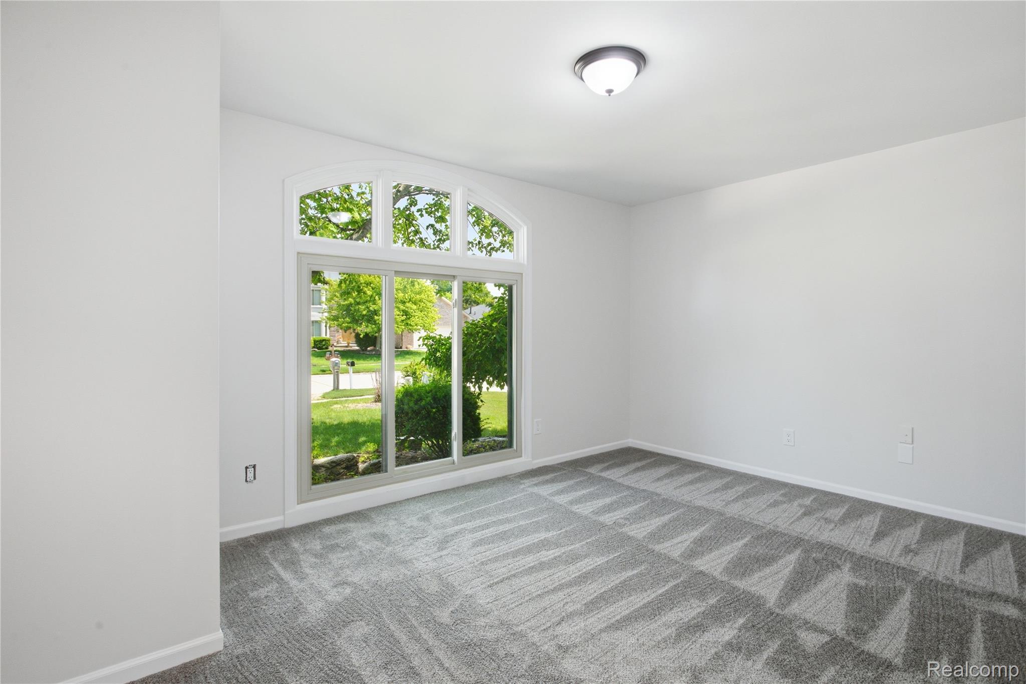 52658 Stag Ridge Drive Macomb, MI 48042 - Photo 18 of 28 Arch-top window with multi-pane transom, neutral wall paint, gray patterned carpet, and flush-mount ceiling light