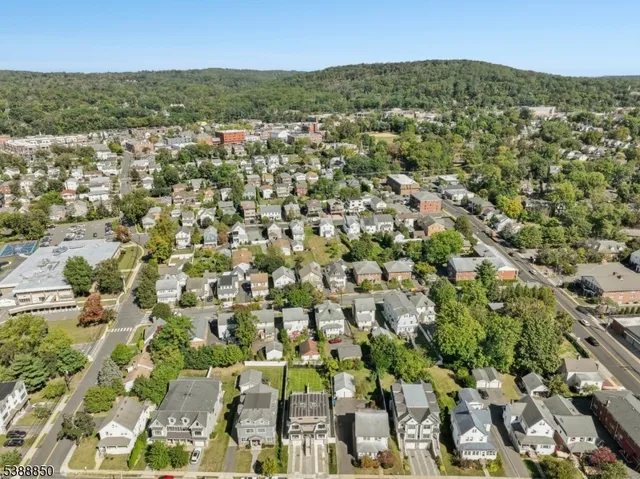 an aerial view of residential houses with outdoor space and trees