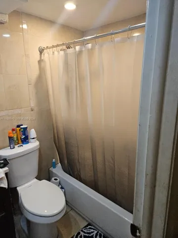 a white toilet sitting next to a shower curtain