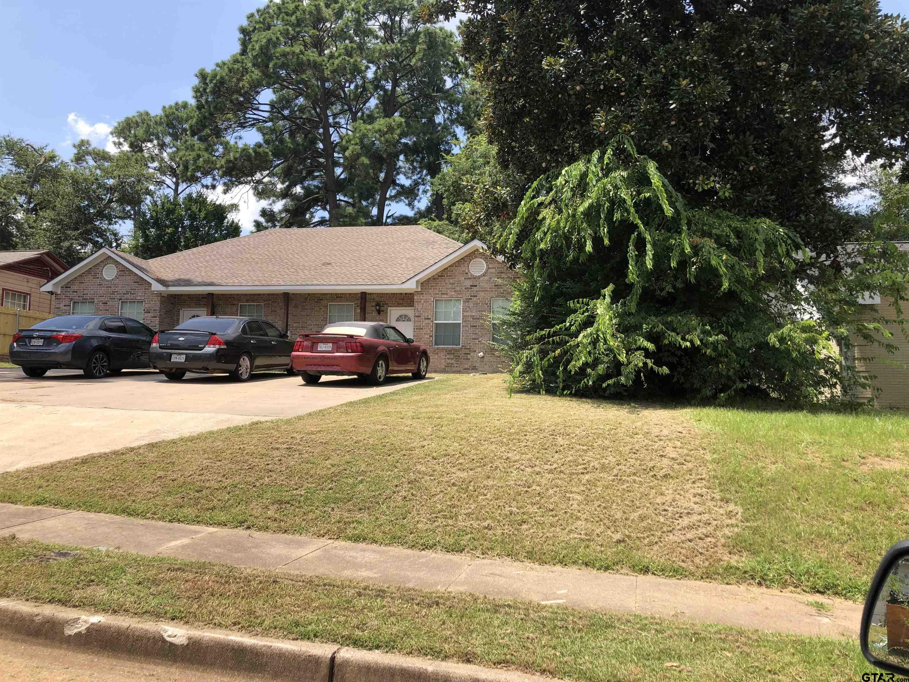 223 South Fenton Avenue Tyler, TX 75702 - Photo 8 of 9 a car parked in front of white house with a yard