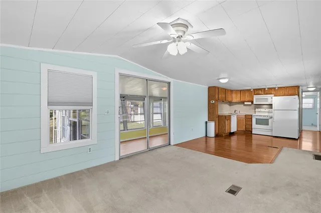 a view of an empty room with a window and kitchen view
