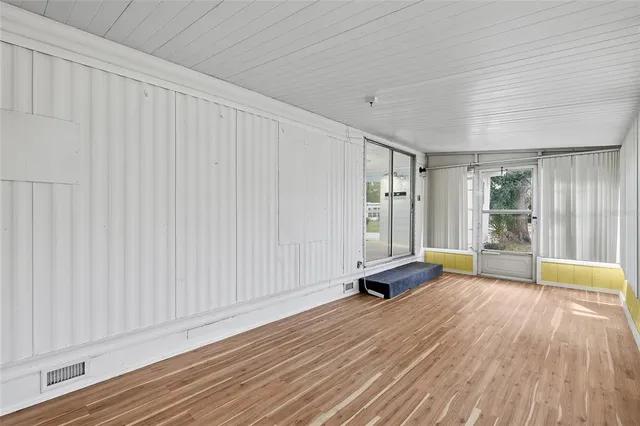 a view of an empty room with window and wooden floor