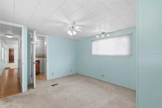 an empty room with a ceiling fan and a window