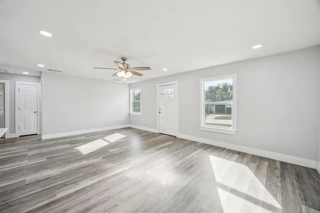 an empty room with wooden floor and windows