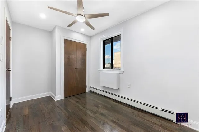 an empty room with wooden floor chandelier fan and windows
