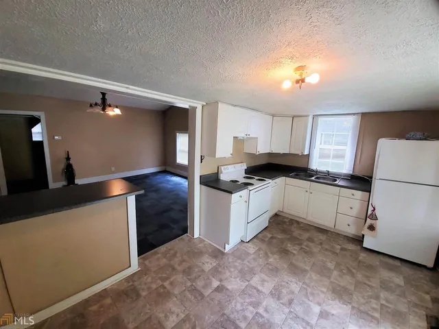 a kitchen with granite countertop white cabinets and white appliances