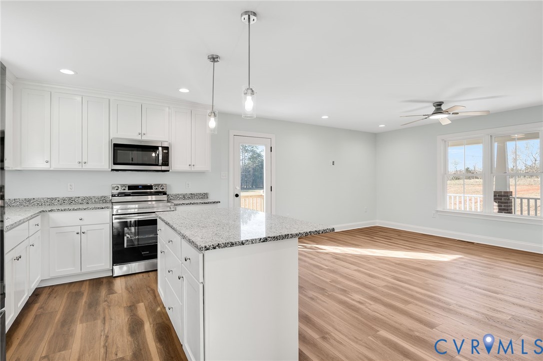2321 Rock Island Road Scottsville, VA 24590 - Photo 11 of 24 a kitchen with granite countertop stainless steel appliances a stove cabinets and a wooden floor