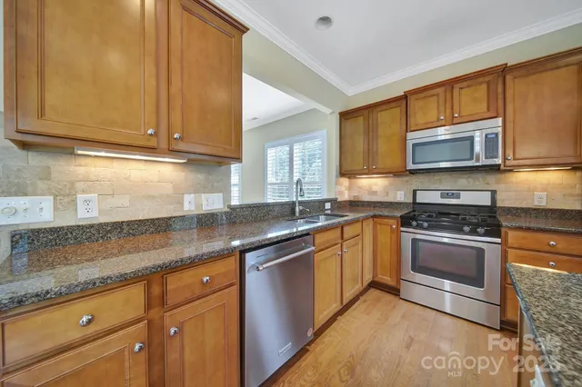 a kitchen with stainless steel appliances granite countertop a sink stove and microwave