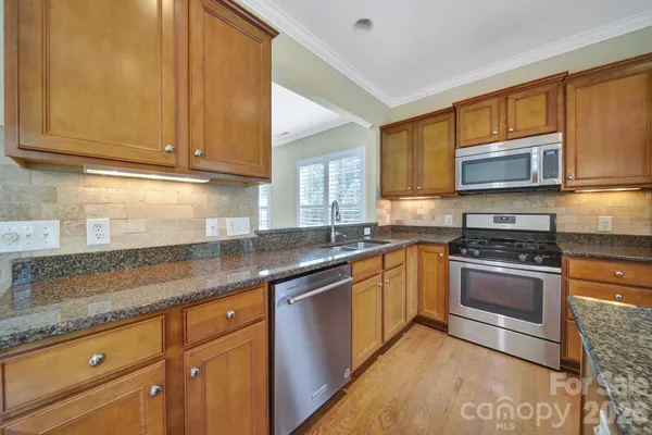 a kitchen with stainless steel appliances granite countertop a sink stove and microwave