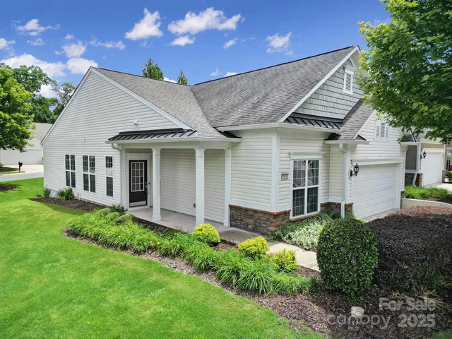 a view of a house with brick walls and a yard with plants