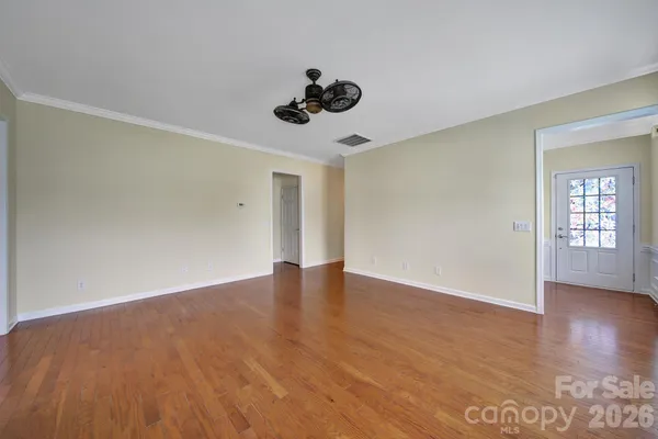 a view of an empty room with wooden floor and a window