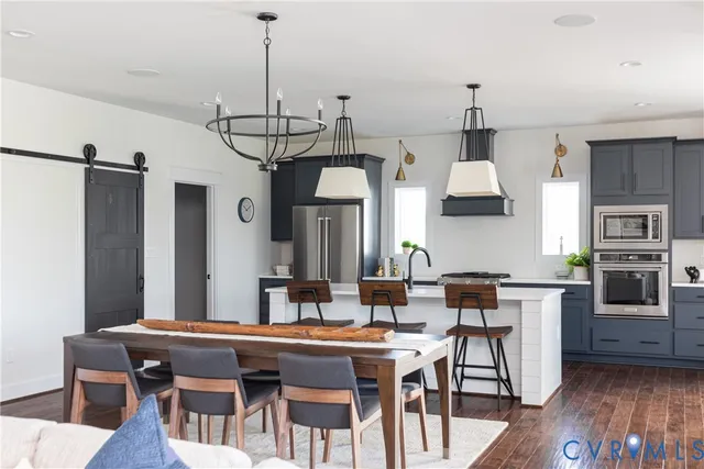 a kitchen with stainless steel appliances granite countertop a kitchen island a stove a table and chairs