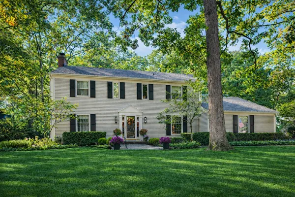 a front view of a house with a garden and trees