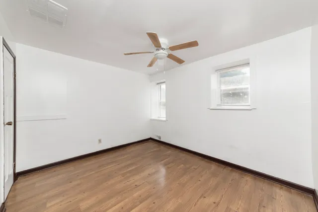 an empty room with a window and a fan