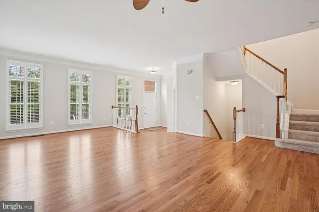 an empty room with wooden floor fan and windows