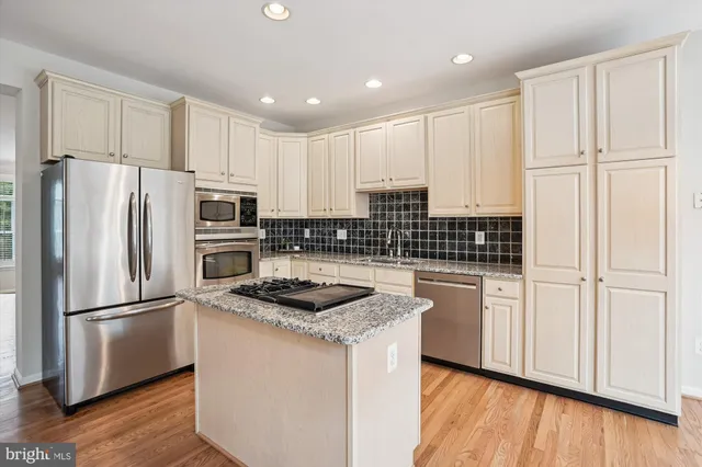 a kitchen with stainless steel appliances granite countertop a stove a sink and white cabinets