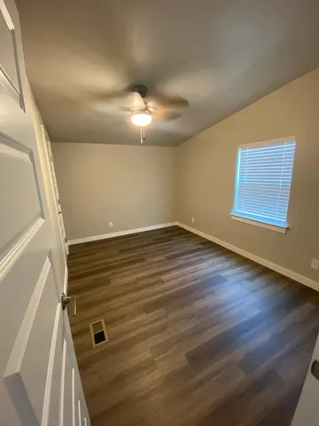 a view of an empty room with wooden floor and windows