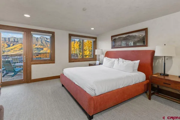a bedroom with a bed lamp and paintings on the wall