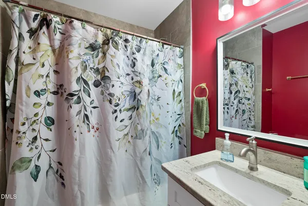 a bathroom with a granite countertop sink a mirror and shower curtain