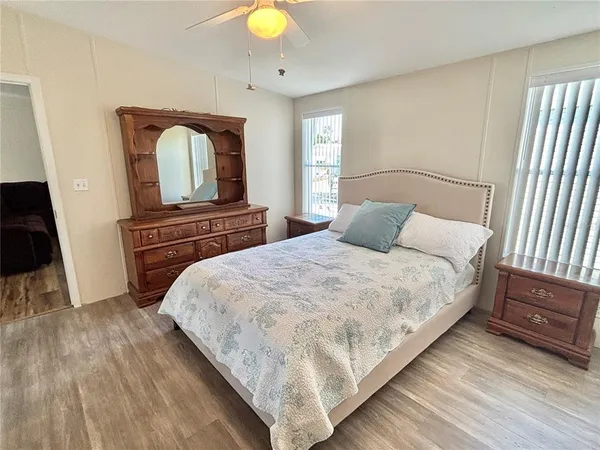 a bedroom with a bed and a dresser with wooden floor