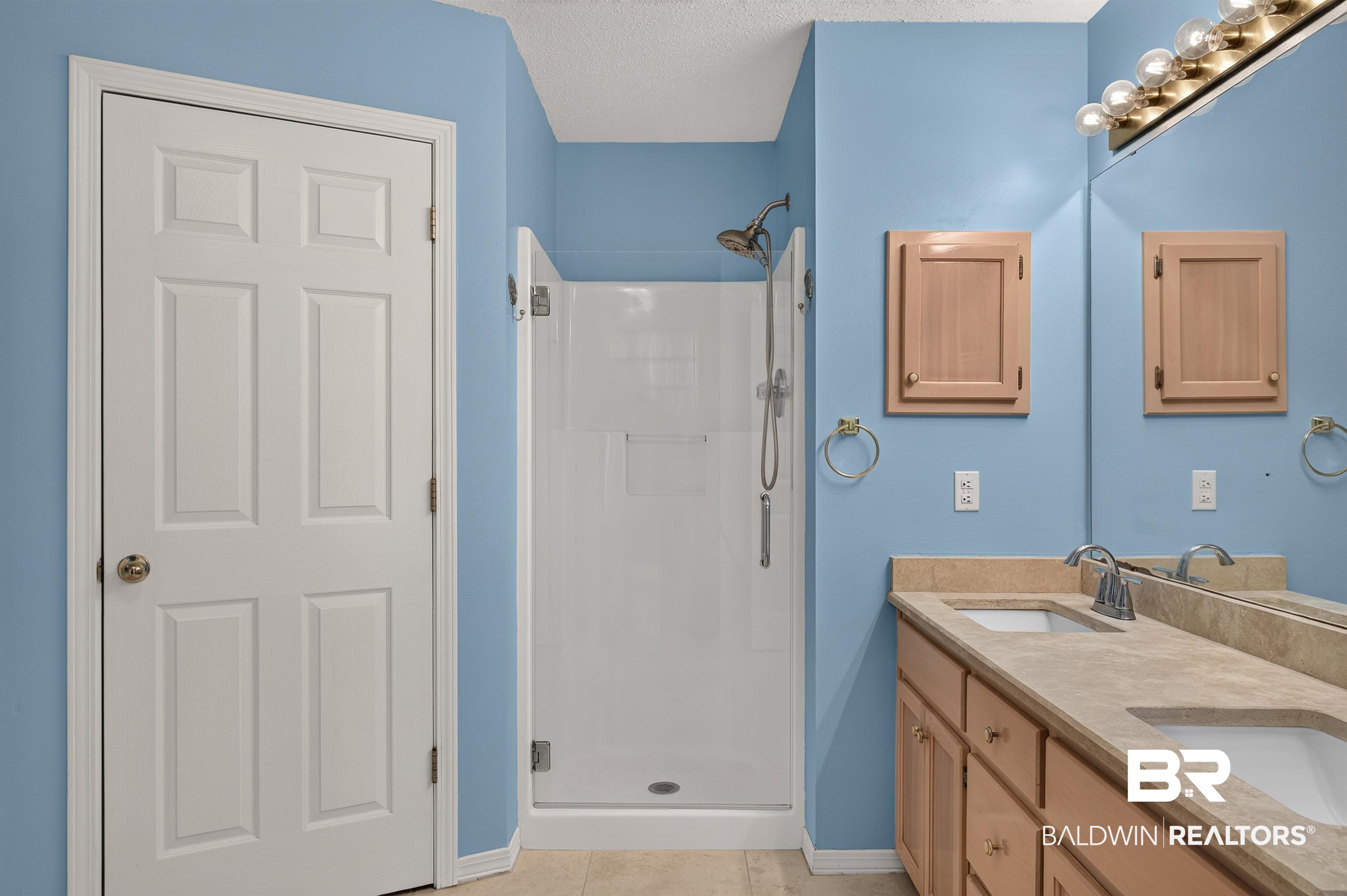 22685 County Road 12 Foley, AL 36535 - Photo 55 of 89 Bathroom featuring a dual sink vanity with a light-toned countertop, a frameless glass shower enclosure, wood-finish cabinetry, and a large mirror with overhead vanity lighting