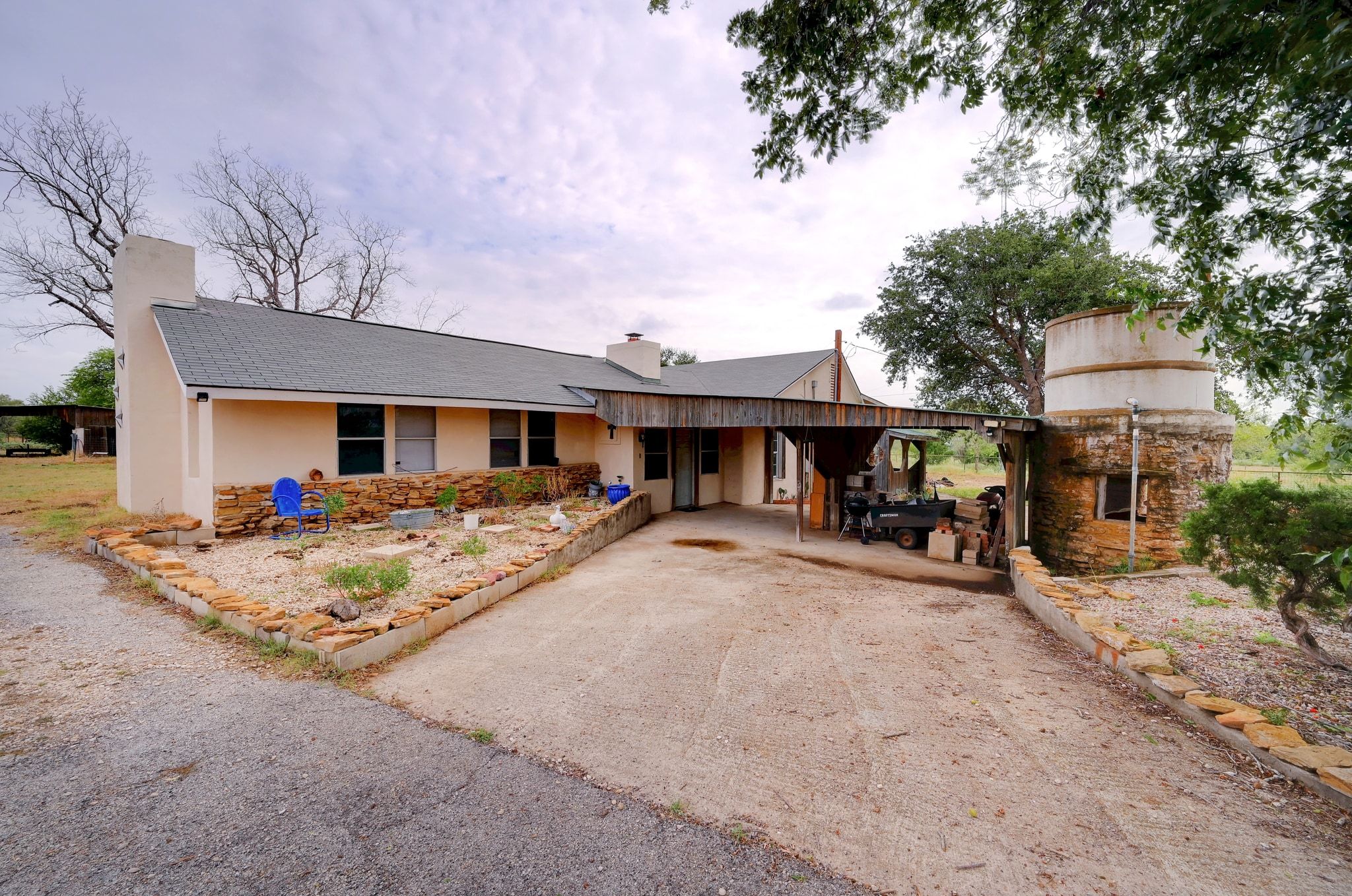 View of front facade with a chimney, a patio area, stone siding, a shingled roof.