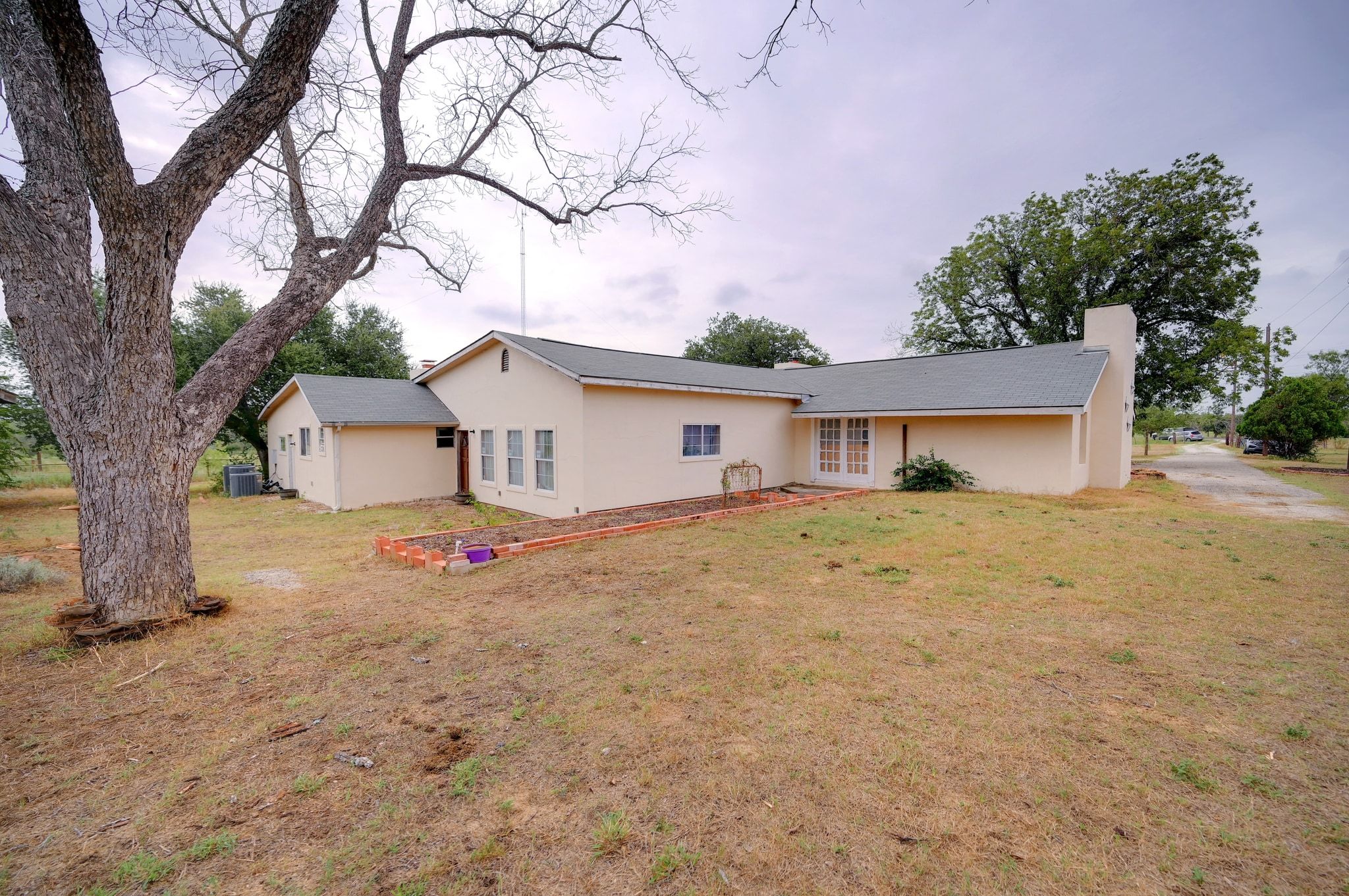 4598 Highway 173 Devine, TX 78016 - Photo 24 of 40 Rear view of house featuring stucco siding, a lawn, and a chimney