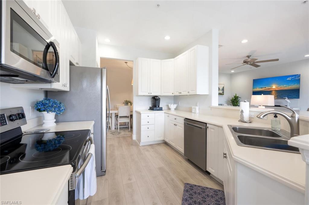 4650 Winged Foot Court, Unit 102 Naples, FL 34112 - Photo 11 of 34 Kitchen with light wood-style flooring, recessed lighting, stainless steel appliances, a sink, and white cabinetry