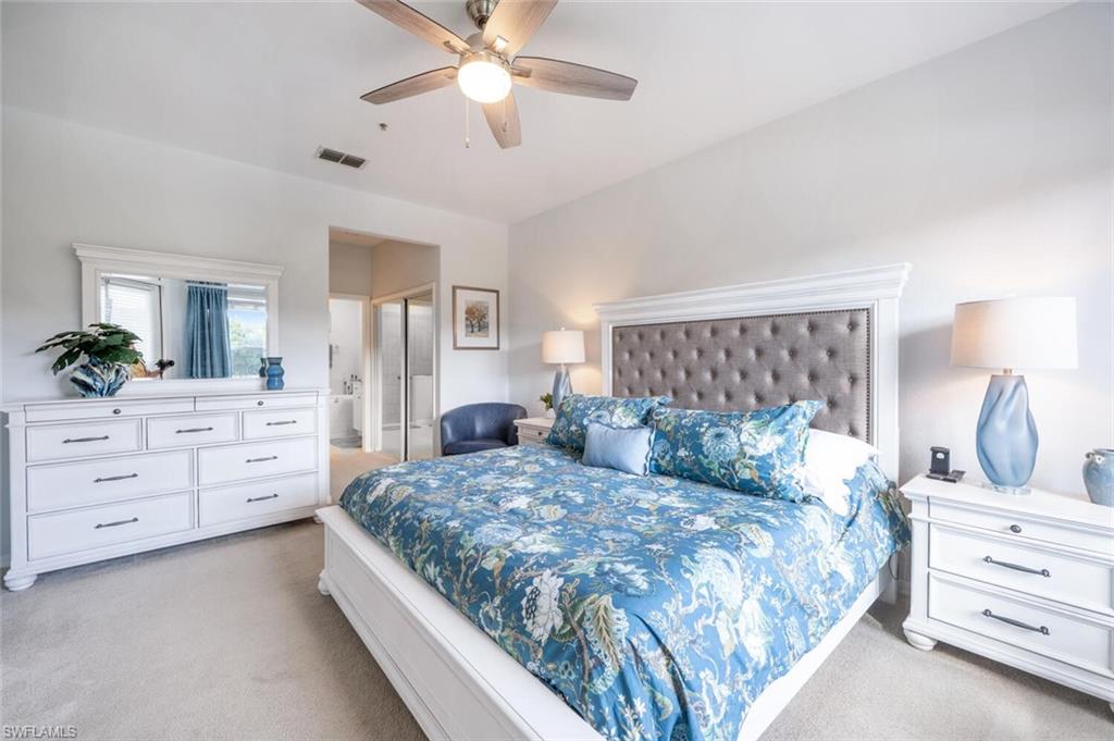 4650 Winged Foot Court, Unit 102 Naples, FL 34112 - Photo 15 of 34 Bedroom with ceiling fan, connected bathroom, visible vents, and light colored carpet