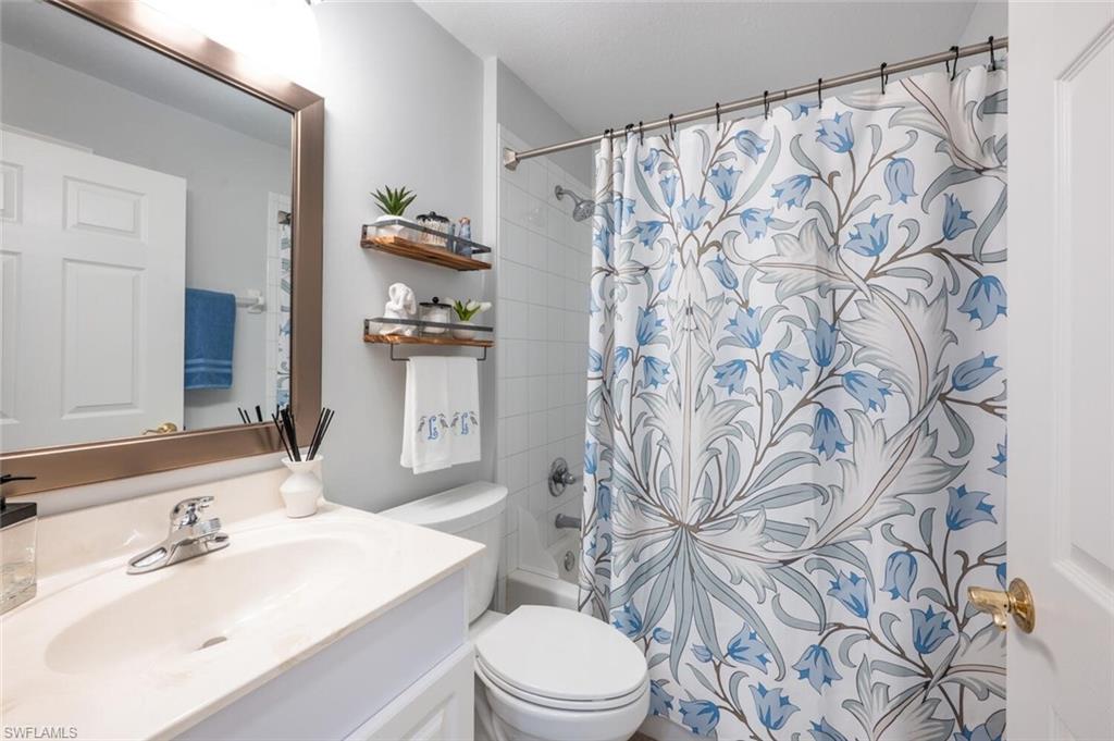 4650 Winged Foot Court, Unit 102 Naples, FL 34112 - Photo 19 of 34 Full bathroom featuring shower / tub combo with curtain, vanity, and toilet