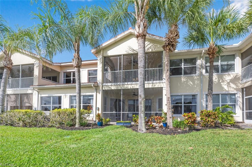 4650 Winged Foot Court, Unit 102 Naples, FL 34112 - Photo 30 of 34 Back of house with a lawn, a sunroom, and stucco siding