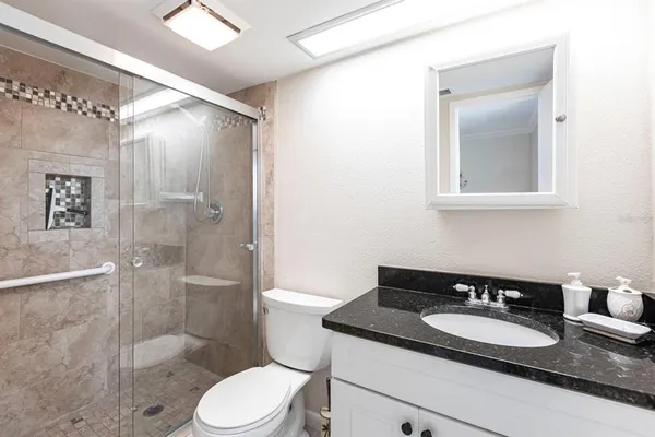 a bathroom with a granite countertop sink toilet a mirror and shower