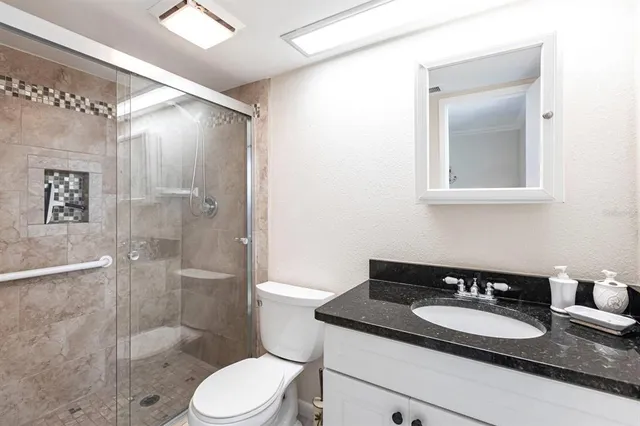 a bathroom with a granite countertop sink toilet a mirror and shower