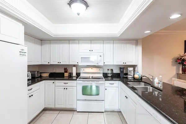 a kitchen with granite countertop white cabinets and white appliances
