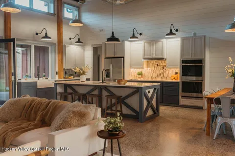 a kitchen with stainless steel appliances kitchen island granite countertop a table chairs sink and cabinets