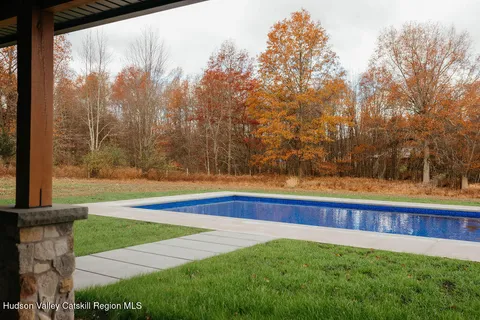 a view of swimming pool with seating space and yard in the back