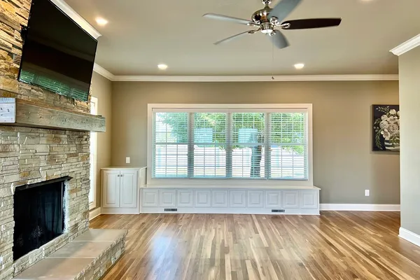 a view of an empty room with wooden floor and a fireplace