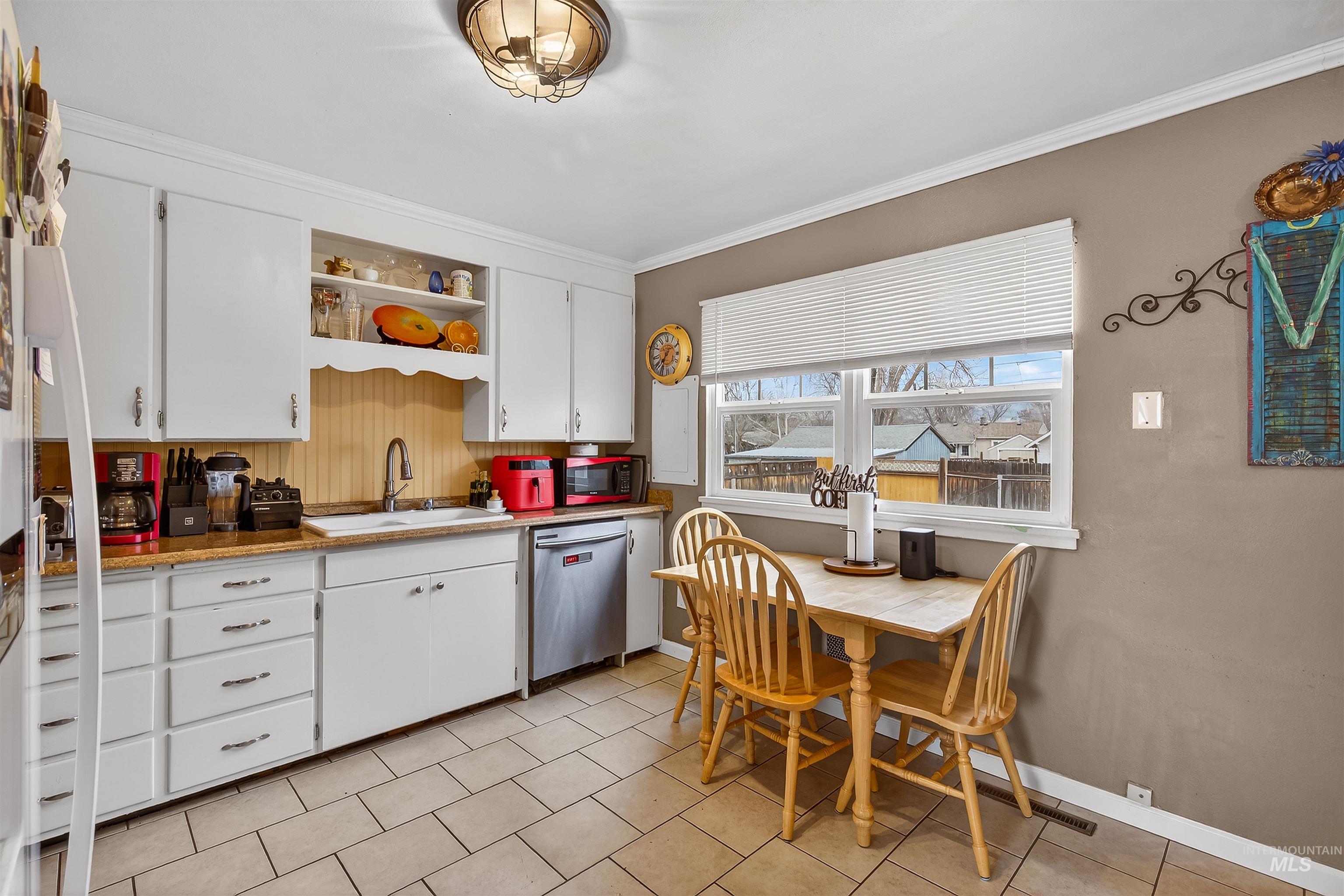835 12th Street Clarkston, WA 99403 - Photo 12 of 39 Kitchen with white cabinetry, dishwasher, ornamental molding, freestanding refrigerator, and light tile patterned floors